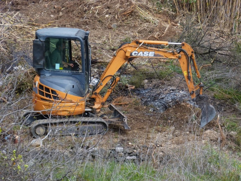 Case skid steer loader at a working site surrounded by grass and branches